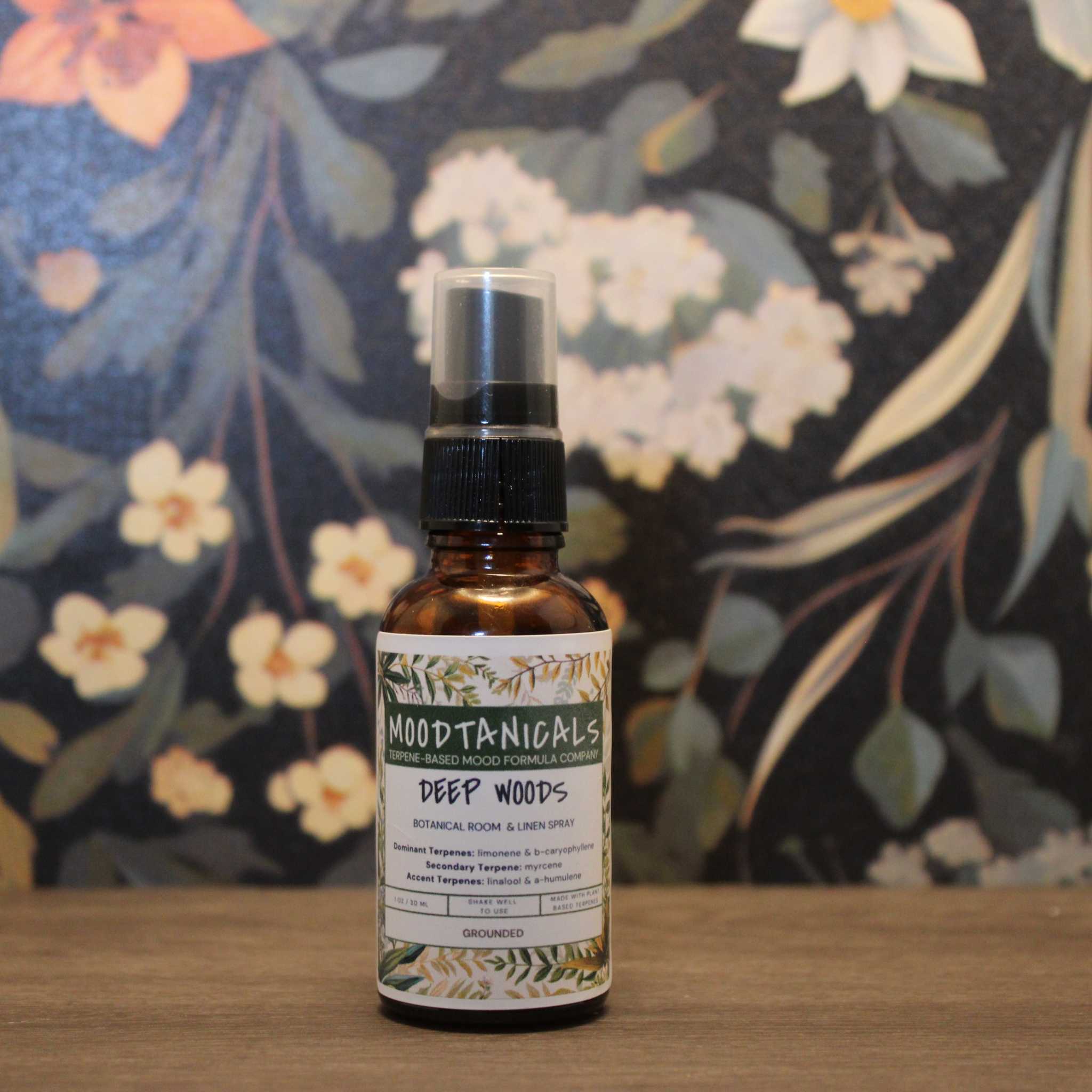 Bottle of 'Deep Woods' room spray by Mood Naturals with a floral background