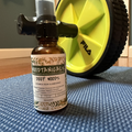 Bottle of Moodtanical's Deep Woods room spray on a textured surface with a yellow exercise wheel in the background.