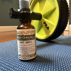 Bottle of Moodtanical's Deep Woods room spray on a textured surface with a yellow exercise wheel in the background.
