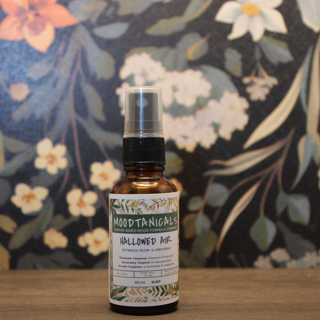 Moodtanicals 'Hallowed Air' bottle on a wooden surface with a floral background