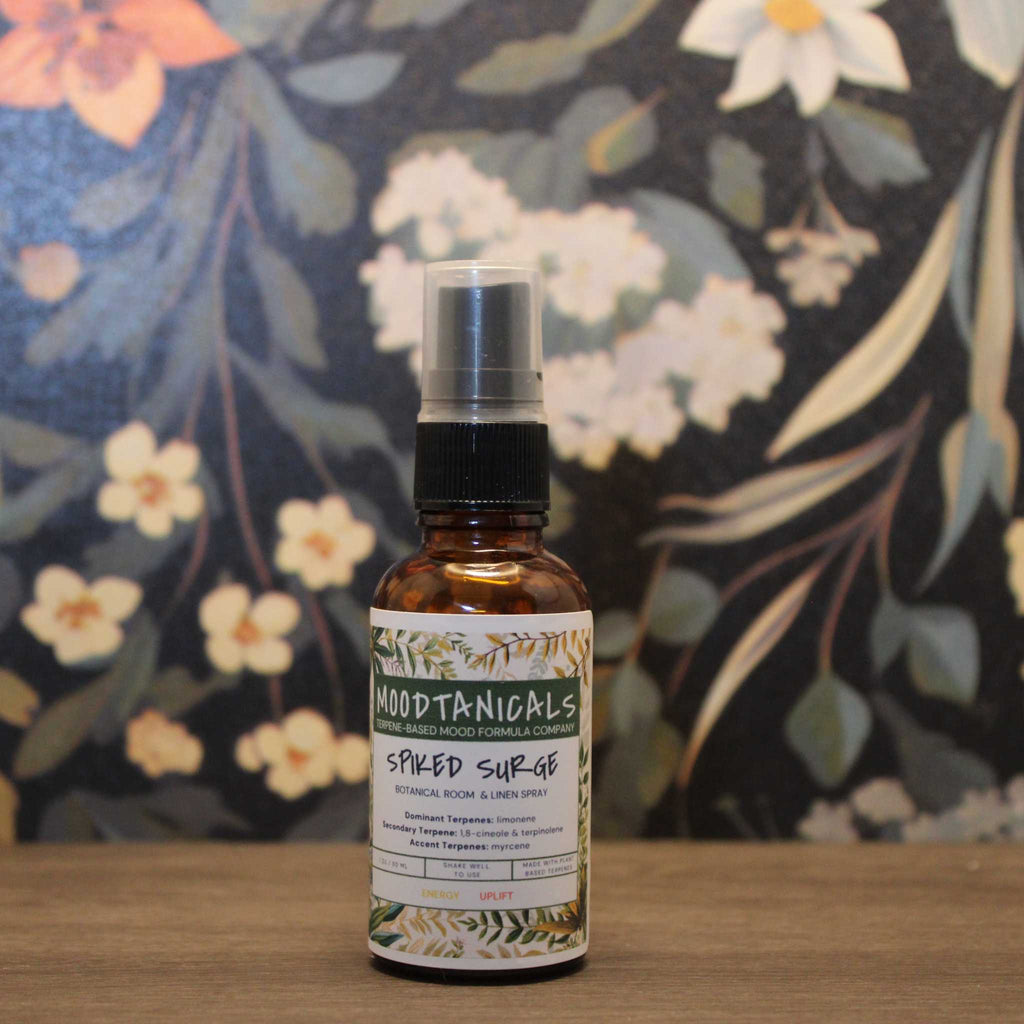 Bottle of 'Moodtanicals Spiced Surge' on a wooden surface with a floral background