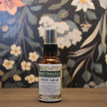 Bottle of 'Moodtanicals Spiced Surge' on a wooden surface with a floral background